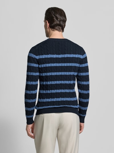 Männermodel trägt Slim Fit Pullover in Strick-Optik von Gant in Blau mit hellblauen Streifen, reine Baumwolle, Ganzkörperansicht Rückansicht.