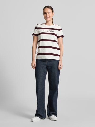 Damesmodel draagt Regular Fit T-shirt uit puur katoen van Tommy Hilfiger met brede witte en bordeauxrode strepen, Ganzkörperansicht von vorne.