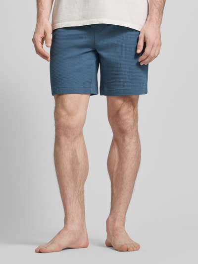 Männermodel trägt Regular Fit Sweatshorts aus Baumwoll-Mix Modell 'AUSTIN' von HUGO in Blau, unifarben, Piqué-Struktur, Nahaufnahme Oberkörper bis Knie.
