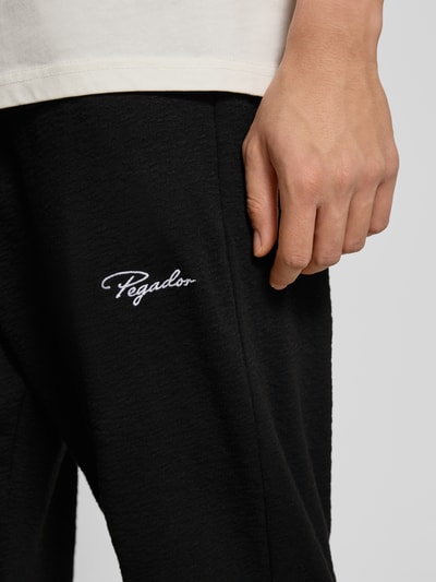 Männermodel trägt Loose Fit Sweathose mit Logo-Stitching Modell 'Signar' von Pegador aus reiner Baumwolle, Nahaufnahme Oberschenkel.