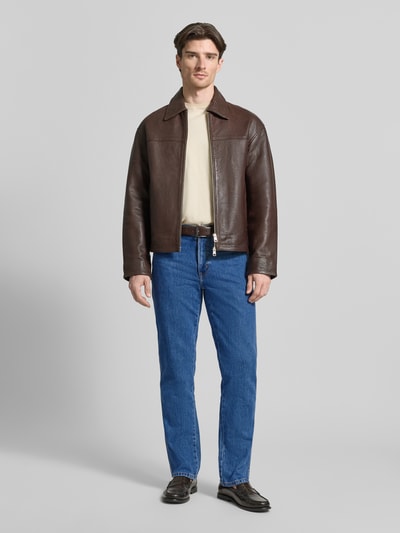 Männermodel trägt Bootcut Jeans mit Label-Detail Modell 'Texas' von Wrangler in Blau, reine Baumwolle, 5-Pocket-Design, Ganzkörperansicht von vorne.