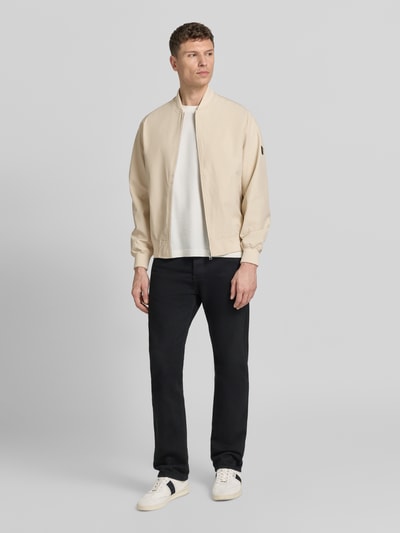 Männermodel trägt Bomberjacke mit Stehkragen Modell 'BLAASPEN' von Jack & Jones Premium in Beige, Material-Mix mit Stretch-Anteil, Lockerer-Schnitt, Reißverschluss, Seitliche Eingrifftaschen, elastische Abschlüsse; Rückenlänge 65 cm, Schulterbreite 48 cm, Brustweite 60 cm, Ärmellänge 66 cm; Ganzkörperansicht von vorne.