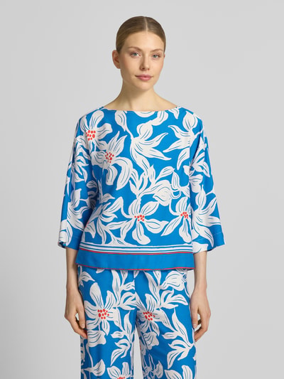 Frauenmodel trägt Relaxed Fit Bluse aus reiner Viskose Modell 'Rylie' von GUIDO MARIA KRETSCHMER WOMAN, floraler Allover-Print in Blau und Weiß, 3/4-Arm, Ganzkörperansicht von vorne. Rückenlänge 55 cm, Ärmellänge 38 cm, Größe 36.