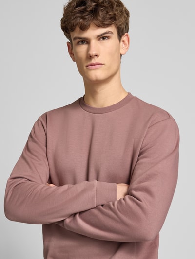 Męski model nosi Regular Fit Sweatshirt aus Baumwoll-Mix Modell 'CERES' od Only & Sons, jednolity kolor, długi rękaw, krój regular fit, bawełna, crew neck, detal z etykietą, tekstura sweat, widok na górną część ciała z przodu.