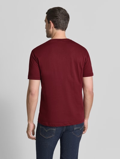 Männermodel trägt Regular fit t-shirt uit puur katoen van GANT in bordeauxrood met glad textuur, ganzekörperaanzicht achteraan.