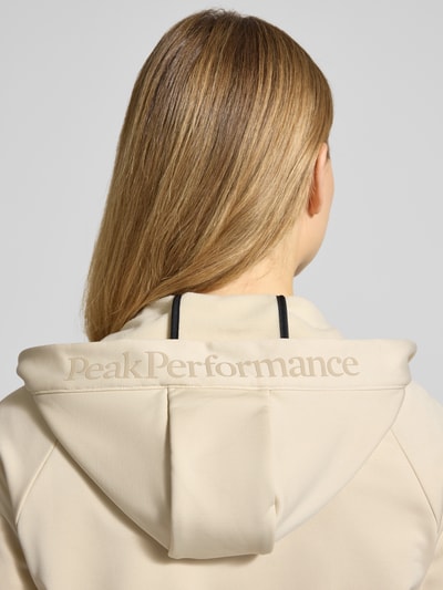 Frauenmodel trägt Softshell-Jacke mit Kapuze Modell 'RIDER' von PEAK PERFORMANCE in Beige, glatte Textur, Detailaufnahme Rückansicht.