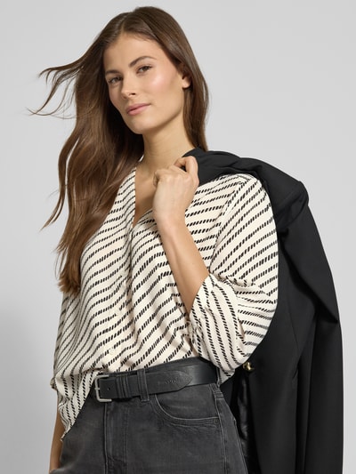 Modelka nosi Relaxed Fit Bluzkę z dekoltem w serek od comma, wzór w czarno-białe paski, rękaw o dł. 1/2, listwa guzikowa, długość tyłu 58 cm, długość rękawów 46 cm, ujęcie z przodu do pasa.