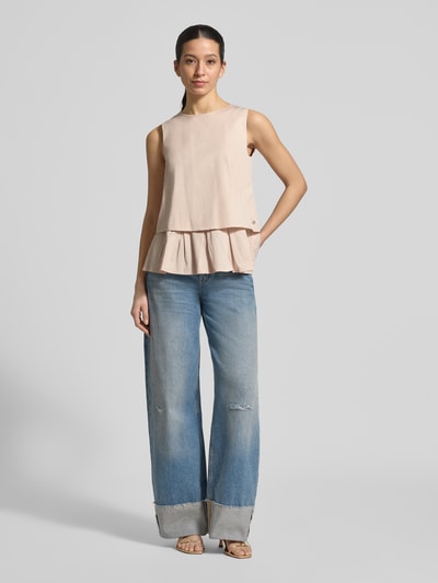 Frauenmodel trägt Blusenshirt mit Volantsaum und Rundhalsausschnitt von Marc Cain aus Baumwoll-Viskose-Mix, Gerader-Schnitt, Rückseite Reißverschluss, Rückenlänge 59 cm bei Größe 36, helle Farbe, glatte Textur, Ganzkörperansicht von vorne.