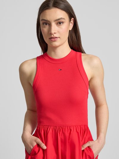 Frauenmodel trägt Midikleid aus reiner Baumwolle von Tommy Jeans in Rot, Optik: Unifarben, Passform: A-Linie, Rundhals, Ärmelform: Ohne, Nahaufnahme Oberkörper.