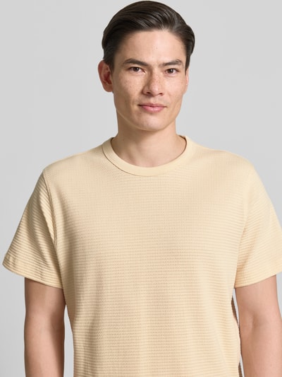 Männermodel trägt Regular Fit T-Shirt aus reiner Baumwolle Modell 'COOPER' von SELECTED HOMME in Beige mit Struktur, Nahaufnahme Oberkörper.