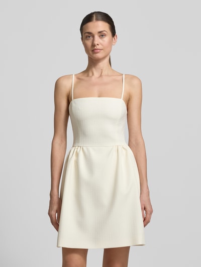 Modelka kobieca nosi Tailliertes Cocktailkleid mit Viskose-Anteil Modell 'Kejani' od HUGO w jednolitym kremowym kolorze, wyraźna struktura tkaniny jacquard, prostokątny dekolt, cienkie ramiączka, długość mini, perspektywa: widok całej sylwetki z przodu.