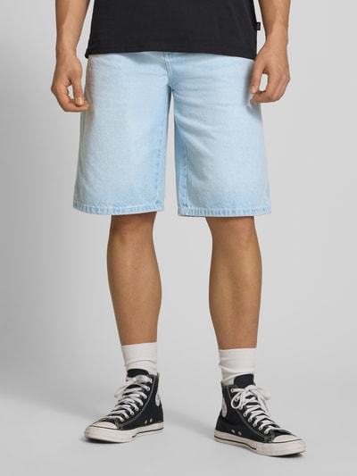 Männermodel trägt Loose Fit Bermudas mit Eingrifftaschen von Dickies aus Reine Baumwolle Denim, hellblau, Ganzkörperansicht von vorne.