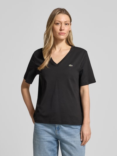 Frauenmodel trägt Relaxed Fit T-Shirt aus reiner Baumwolle von Lacoste in Schwarz mit Logo-Stitching und V-Ausschnitt, Ganzkörperansicht von vorne.