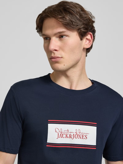 Männermodel trägt Regular Fit T-Shirt mit Logo-Print Modell 'Buster' von JACK & JONES in Dunkelblau, Reine Baumwolle, Nahaufnahme Oberkörper. Rückenlänge bei Größe M: 71 cm.