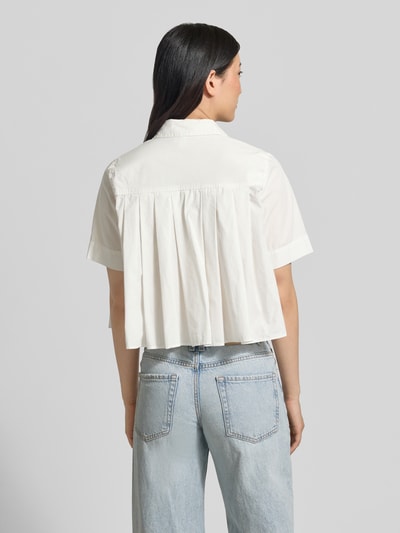 Frauenmodel trägt Bluse mit verdeckter Knopfleiste Modell 'SKYMA' von YAS aus reiner Bio-Baumwolle in Weiß, Loose-Fit, Ganzkörperansicht Rückansicht.