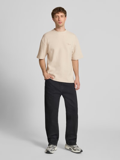 Männermodel trägt Oversized T-Shirt mit Strukturmuster und Label-Stitching von Pegador aus Reine Baumwolle, Creme, Ganzkörperansicht von vorne.
