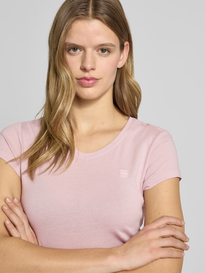 Kobiece model prezentuje T-shirt mit Label-Stitching od G-Star Raw z bawełny, krój slim fit, prążkowany okrągły dekolt, różowy, zbliżenie na górną część ciała.