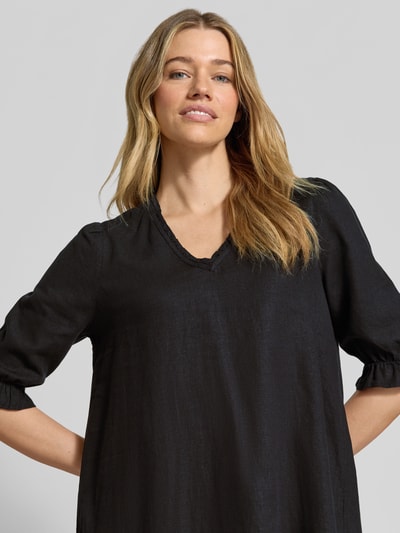 Frauenmodel trägt knielanges Kleid aus Leinen-Viskose-Mix Modell 'FALAKKA' von B.Young in Schwarz mit Rüschen, gerader Schnitt, Nahaufnahme Oberkörper. Rückenlänge 95 cm, Brustweite 38 cm, Ärmellänge 39 cm.