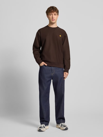 Männermodel trägt Sweatshirt mit Label-Stitching von Carhartt Work In Progress, Braun, Baumwoll-Mix, Lockerer-Schnitt, Ganzkörperansicht von vorne.