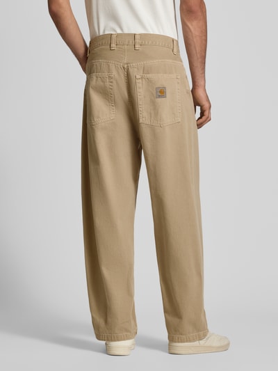 Männermodel trägt Jeans mit Eingrifftaschen Modell 'Brandon' von Carhartt Work In Progress, beige, lockerer Schnitt, reine Baumwolle, Ganzkörperansicht Rückansicht.