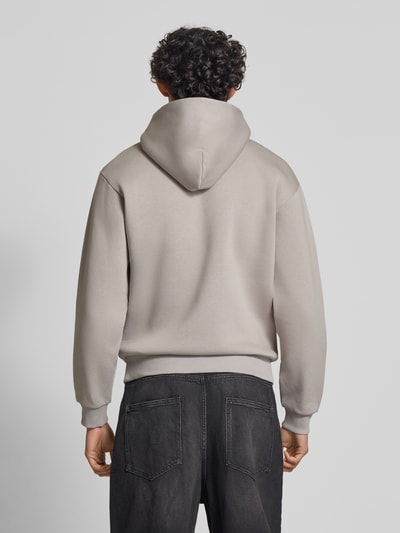 Männermodel trägt Hoodie mit Känguru-Tasche von REVIEW in Beige, lockere Passform, Baumwollmischung, Ganzkörperansicht Rückansicht.