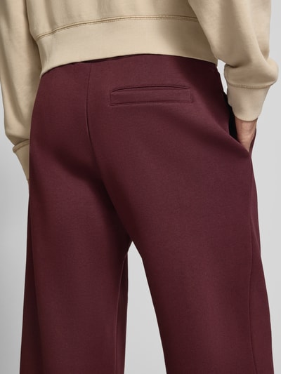 Männermodel trägt Straight Fit Sweatpants aus Baumwoll-Mix mit Label-Detail von REVIEW in Dunkelrot, Detailaufnahme Rückansicht.