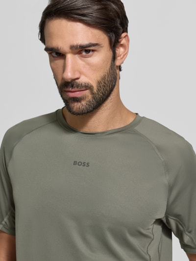 Männermodel trägt Regular Fit T-Shirt mit Flatlock-Nähten Modell 'TEE ACTIVE 1' von BOSS Green in Optik: Unifarben, Label-Print, Rundhals, Kurzarm, Raglanärmel, leichtes und schnell trocknendes Stretch-Gewebe, Nahaufnahme Oberkörper.
