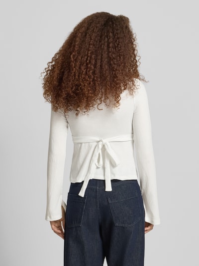 Frauenmodel trägt Regular Fit Langarmshirt in Wickel-Optik Modell 'PELLY' von Only, Weiß mit Struktur-Muster, Ganzkörperansicht Rückansicht.