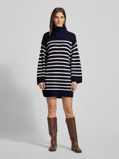 Frauenmodel trägt Mini-Strickkleid aus Woll-Kaschmir-Mix Modell 'AREENA' von Lauren Ralph Lauren, oversized, marine mit weißen Streifen, Rollkragen, gerippte Abschlüsse, Minilänge, Ganzkörperansicht von vorne.