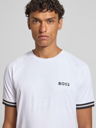 Männermodel trägt Regular Fit T-Shirt mit Label Print Modell 'TOC SERVE 2' von BOSS Green in Optik: Unifarben mit Kontraststreifen, Logo-Print, Rundhals, Kurzarm, elastischem Ärmelabschluss, Materialverarbeitung: Stretch, Ganzkörperansicht von vorne.