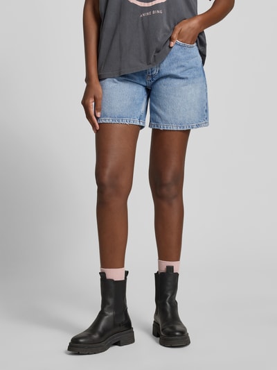 Frauenmodel trägt Regular Fit Shorts in Denim-Optik von Anine Bing aus reiner Baumwolle, 5-Pocket-Design, hellblaue Farbstruktur, Nahaufnahme Oberschenkel.