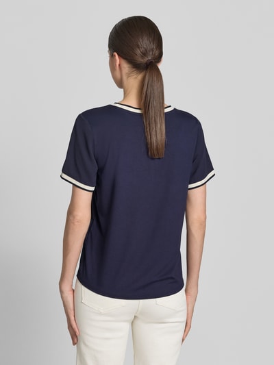 Kobieta modelka nosi Regular Fit Kurzarmbluse mit Rundhalsausschnitt od Christian Berg Woman Selection w kolorze granatowym, krótki rękaw z elastycznym wykończeniem, prosty krój, długość tyłu 58 cm w rozmiarze 36, długość rękawa 22 cm, gładka tekstura, widok całej sylwetki z tyłu.