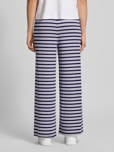 Vrouwenmodel draagt Hose im Allover-Look mit Tunnelzug van Gina Tricot, materiaalmix met viscose, wide leg, all-over look, elastische band, tunnelkoord, bandwijdte bij maat S 40 cm, binnenbeenlengte bij maat S 72 cm, volledige lichaamsopname achterkant.