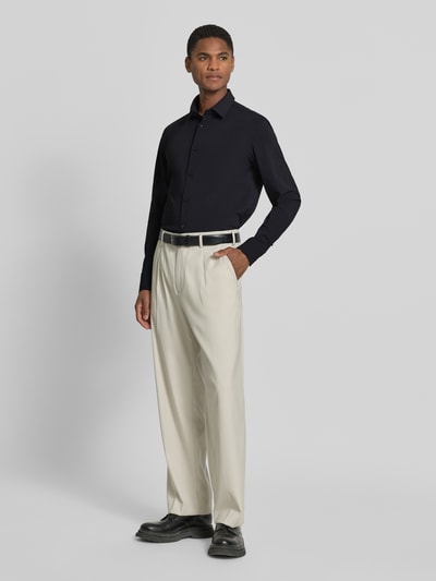 Männermodel trägt Slim Fit Businesshemd mit Kentkragen Modell 'P-HANK-S' von BOSS, unifarben, Performance-Stretch-Jersey, Ganzkörperansicht von vorne.