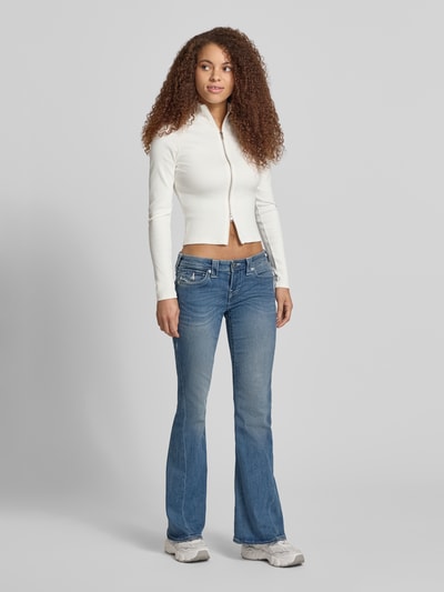 Frauenmodel trägt blaue Flared Jeans Modell 'JOEY' von TRUE RELIGION aus Baumwoll-Mix mit Stretch-Anteil, Low-Rise, Ganzkörperansicht von vorne.