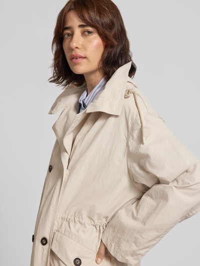 Vrouwenmodel draagt Relaxed Fit Trenchcoat in kreuklook van Marc O'Polo in lichtbeige, zachte textuur, detailopname bovenlichaam, Dames trenchcoat.