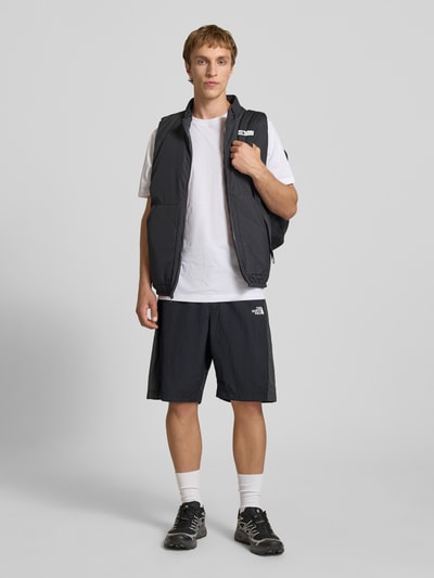 Männermodel trägt schwarze Shorts mit Logo und Gürtel von The North Face, Regular-Fit, elastischer Bund, Bundweite 42 cm, Innenbeinlänge 24 cm, Ganzkörperansicht von vorne.