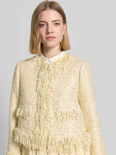 Modelka nosi Regular Fit Jacke in Bouclé-Optik von Rich & Royal, mieszanka materiałów z mieszanką bawełny, cekinowe obszycie na całej powierzchni, imitacja bouclé, kolor kremowy z żółtym, długość tyłu w rozmiarze 36: 46 cm, szerokość w rozmiarze 36: 42 cm, długość rękawów w rozmiarze 36: 51 cm, tekstura wyraźnie zarysowana, widoczna struktura materiału, nahaufnahme oberkörper.