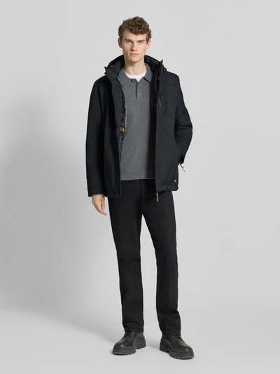 Männermodel trägt Regular Fit Parka mit Kapuze Modell 'ROCKO' von CARS JEANS, dunkle Farben, verdeckter Reißverschluss, Ganzkörperansicht von vorne.