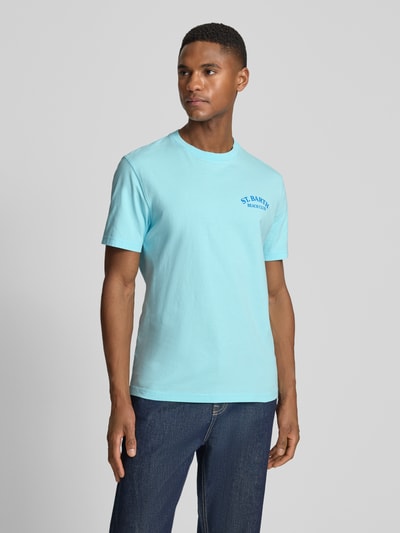Męski model nosi t-shirt z bawełny MC2 Saint Barth, model 'PORTLAND', krój regular fit, nadruk z logo, okrągły dekolt, jasnoniebieski; całkowity widok z przodu. Długość tyłu w rozmiarze M: 67 cm.