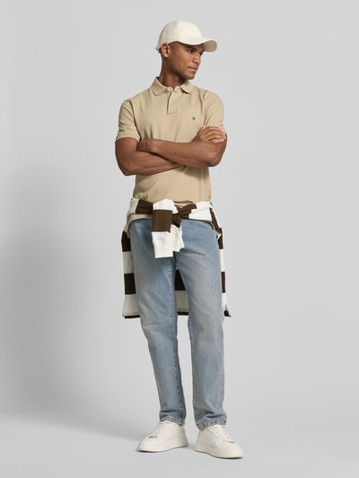 Męski model nosi Regular Fit Poloshirt aus Baumwoll-Mix od Tommy Hilfiger, efekt: jednolity kolor, wyhaftowane logo, kołnierzyk polo, zapięcie na 2 guziki, krótki rękaw, dół z rozcięciem, wykończenie: pika, mieszanka bawełny. Ganzkörperansicht von vorne.