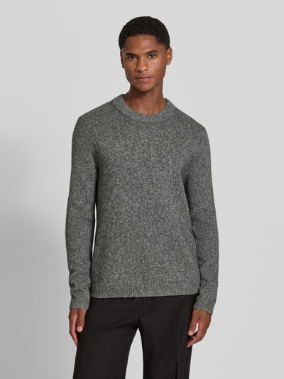 Männermodel trägt Wollpullover aus reiner Wolle Modell 'Harlow' von Tiger of Sweden in grijs, recht model, ronde hals, ribboorden, mix van wol en jak, ruglengte maat M 63 cm, mouwlengte maat M 67 cm, Ganzkörperansicht von vorne.