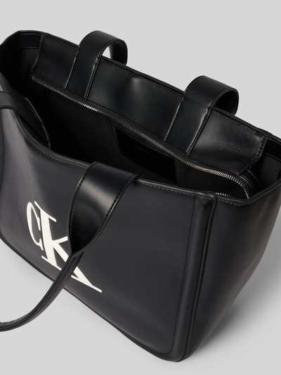 Produktfoto, Tote Bag in Leder-Optik von CK Calvin Klein in Schwarz mit Logo-Print, Hauptfach mit Reißverschluss, Tragehenkel, Maße 35x28x15 cm, Schulterriemen 56 cm, strukturierte glatte Oberfläche, detailreiche Ansicht des Innenraums