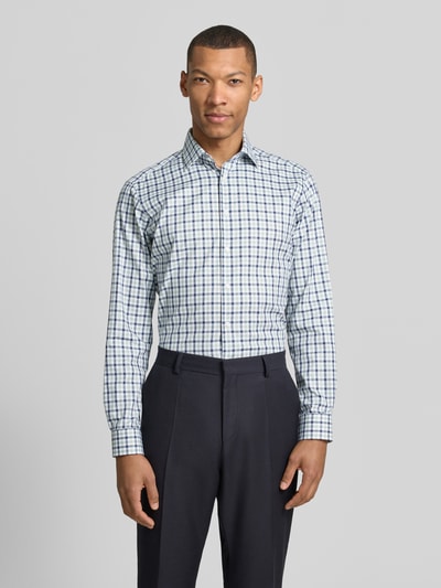 Męski model nosi Regular Fit Business-Hemd mit Kentkragen od Christian Berg Men, biała tkanina w granatową i zieloną kratę, bawełna, krój regular fit, kołnierz kent, listwa guzikowa, mankiety sportowe, zaokrąglony dół, długość tyłu w rozmiarze 39/40: 78 cm, szerokość w rozmiarze 39/40: 47 cm, długość rękawa w rozmiarze 39/40: 65 cm, widok całej sylwetki z przodu.