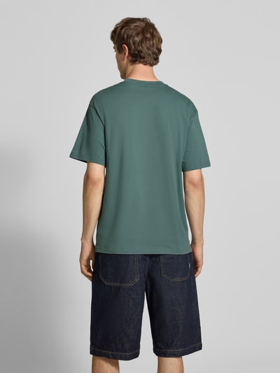 Mężczyznamodel nosi męski t-shirt z bawełny, krój regular fit, model 'Madison' z wyhaftowanym logo, okrągły dekolt, Carhartt Work In Progress, długość tyłu w rozmiarze M: 75 cm, widok całej sylwetki z tyłu.