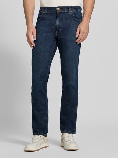 Männermodel trägt Straight Fit Jeans aus Baumwoll-Mix Modell 'Greensboro' von Wrangler in Dunkelblau, glatte Textur, Ganzkörperansicht von vorne. Herren Straight Fit Jeans von Wrangler.