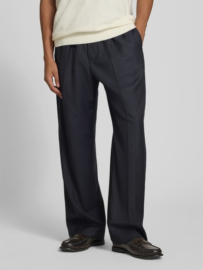 Männermodel trägt dunkelblaue Stoffhose aus Woll-Mix von Officine Générale, Straight Fit mit elastischem Bund und Tunnelzug, Nahaufnahme Unterkörper, Bundfalten sichtbar, Kontext: Herren Stoffhose, Innenbeinlänge 40 cm, Bundweite 81 cm.