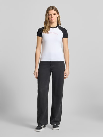 Vrouwenmodel draagt Slim Fit T-shirt met ronde hals en logo van Guess Jeans uit mix van katoen en elastaan, ruglengte maat S 53 cm, ganzebodyvooraanzicht.