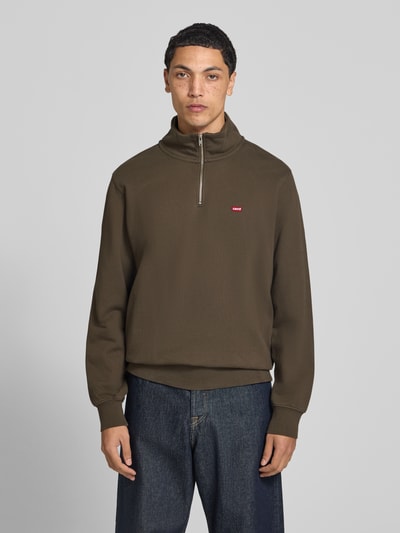 Männermodel trägt Regular Fit Troyer aus reiner Baumwolle von Levi's® in Olivgrün, schlichter Look, glatte Textur, Ganzkörperansicht von vorne.
