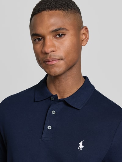 Männermodel trägt Slim Fit Poloshirt aus Baumwoll-Mix von Polo Ralph Lauren, Optik: Unifarben, Logo-Detail, Nahaufnahme Oberkörper.